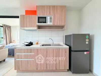 Modern kitchen with wooden cabinets, microwave, and fridge in a stylish apartment.