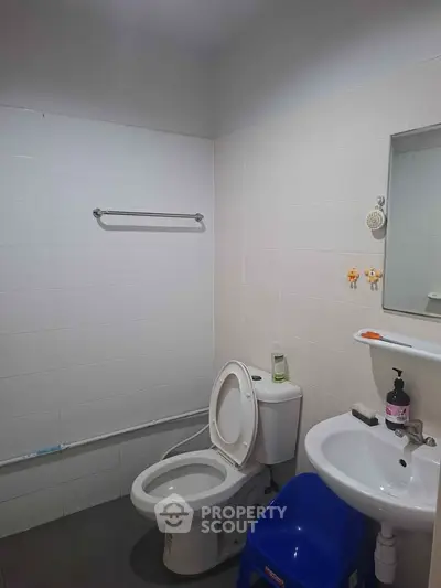 Modern bathroom with white tiles, toilet, and sink, ideal for a minimalist home design.