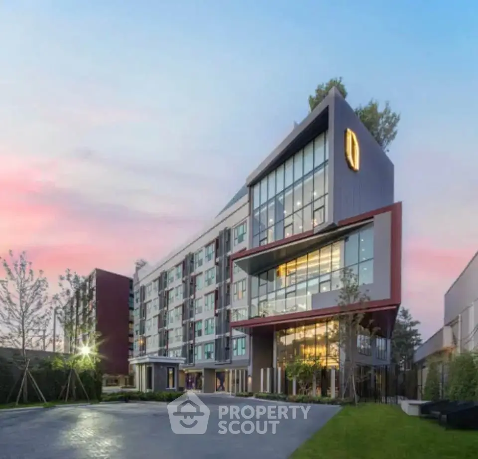Modern apartment building with sleek design and large windows at sunset.