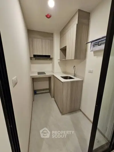 Modern compact kitchen with sleek cabinetry and built-in appliances in a stylish apartment.