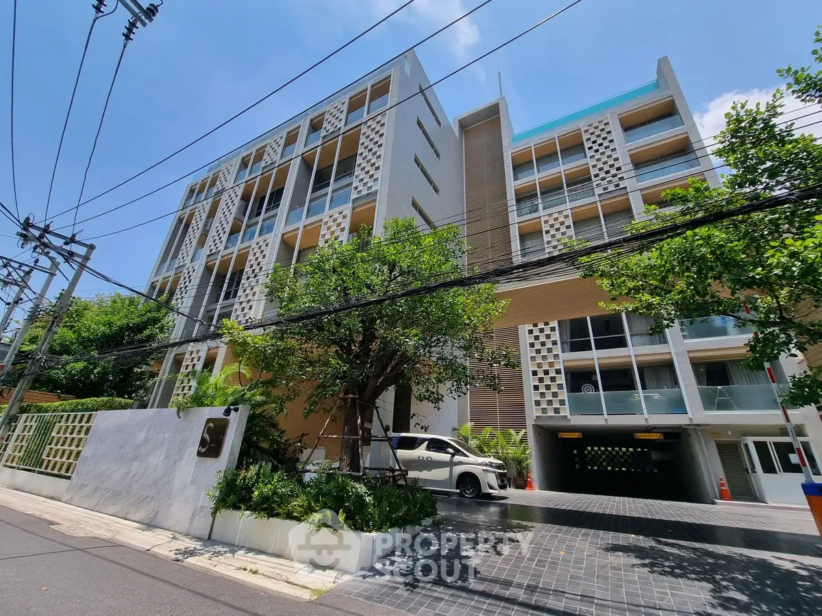 Modern apartment building with lush greenery and sleek design in urban setting.