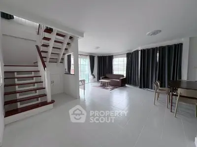 Spacious modern living room with staircase and large windows in a bright, open layout.