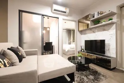 Modern living room with stylish decor and open layout, featuring a cozy sofa and sleek TV setup.