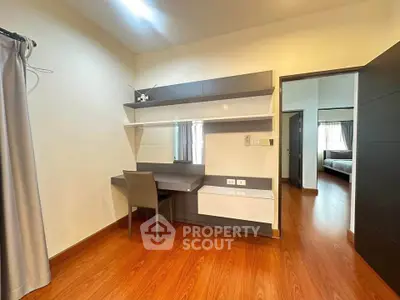 Modern study room with sleek desk and chair, wooden flooring, and ample natural light.