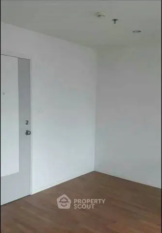 Minimalist empty room with wooden flooring and white walls, ready for customization.