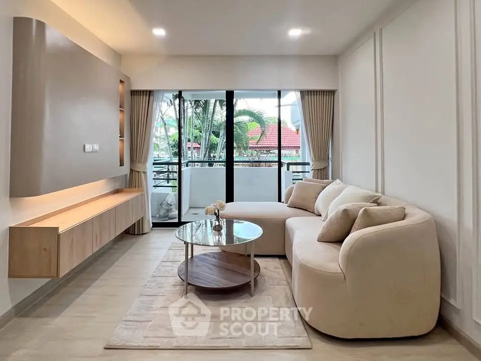 Modern living room with elegant furniture and large windows opening to a balcony with a view.