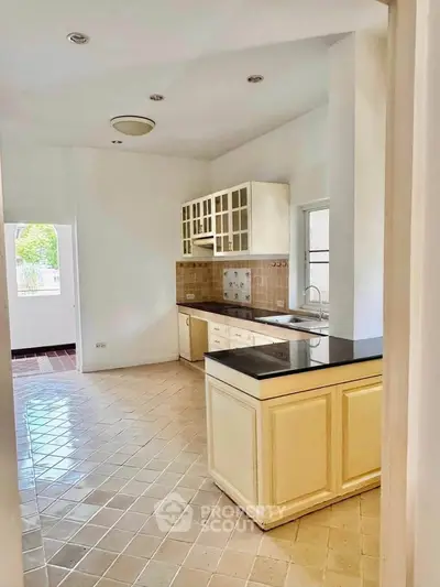 Spacious kitchen with elegant tile flooring and ample natural light, featuring a sleek countertop and classic cabinetry.