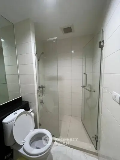 Modern bathroom with glass shower enclosure and sleek white tiles.