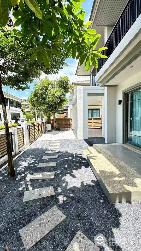 Modern house exterior with spacious garden and pathway under lush greenery