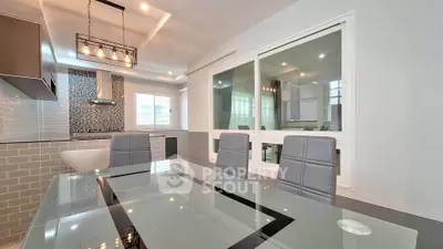 Modern dining area with glass table and stylish kitchen in open layout