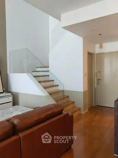 Modern living room with sleek staircase and leather sofa in stylish apartment