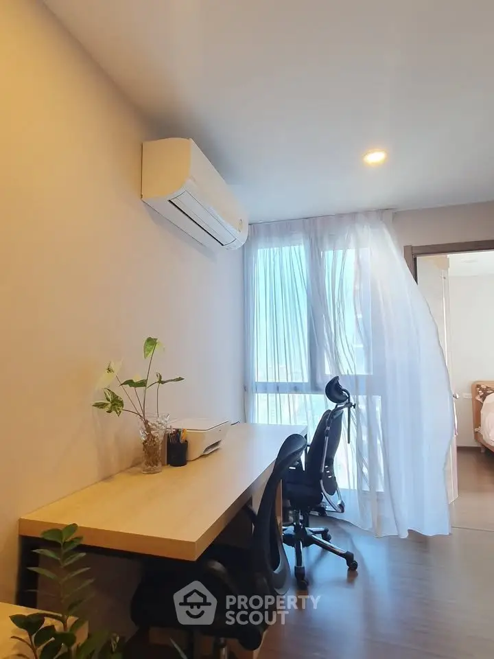 Modern study room with desk, chairs, and air conditioning in bright apartment.