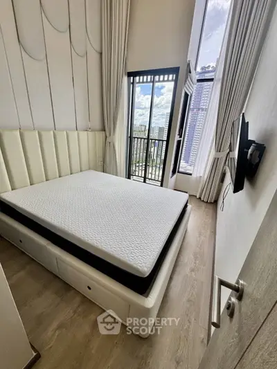 Modern bedroom with large window and city view, featuring a stylish bed and sleek decor.