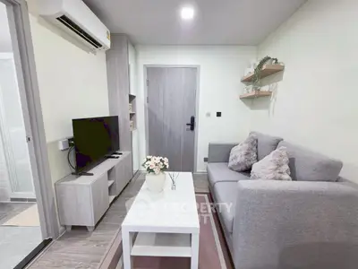 Modern living room with cozy gray sofa, TV, and stylish decor in a compact apartment.