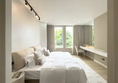 Luxurious bedroom with modern decor and large windows offering natural light.