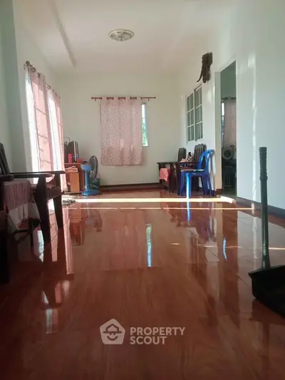 Spacious living room with glossy wooden flooring and natural light