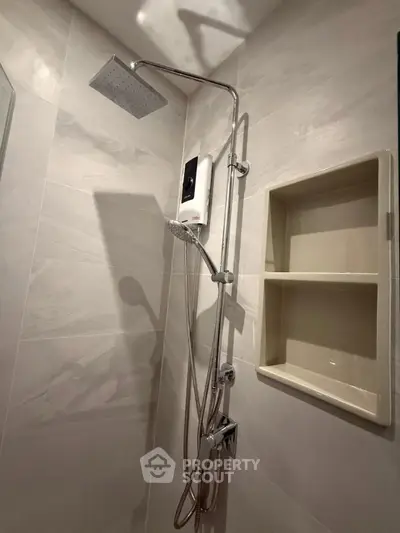 Modern bathroom with sleek showerhead and built-in shelving, perfect for a contemporary home.
