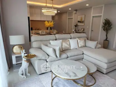 Luxurious living room with elegant decor and open kitchen layout, featuring plush seating and modern lighting.