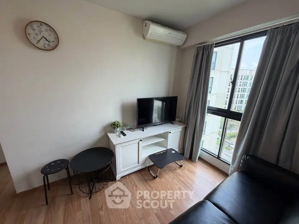 Cozy living room with modern decor, featuring a TV, air conditioning, and a view of the cityscape.