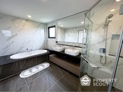 Luxurious modern bathroom with dual sinks, bathtub, and glass shower enclosure.