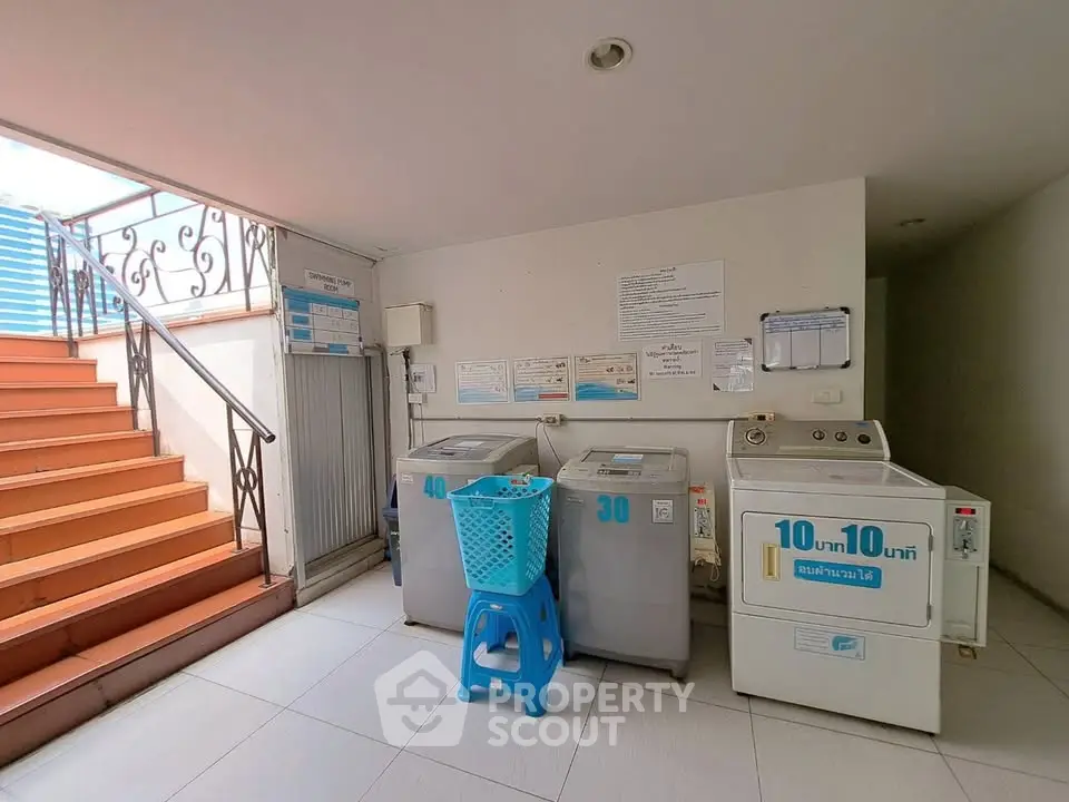 Laundry area with washing machines and a basket in a residential building.