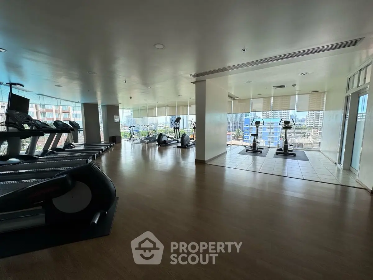 Spacious gym with modern equipment and city view in luxury building.