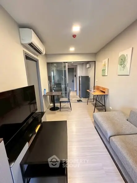 Modern living room with sleek furniture and open layout, featuring a cozy sofa and wall-mounted TV.