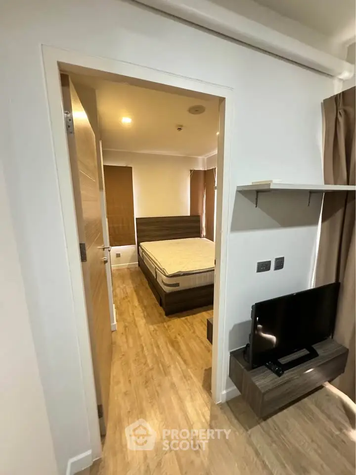 Modern bedroom with wooden flooring and sleek furniture, featuring a cozy bed and a flat-screen TV.