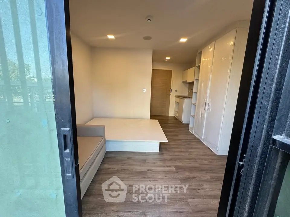 Modern studio apartment with sleek wooden flooring and compact kitchen area.