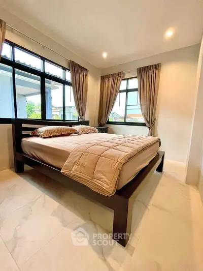 Spacious bedroom with large windows and modern decor, offering abundant natural light and a cozy atmosphere.