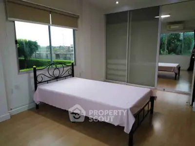 Spacious bedroom with large window and mirrored closet doors, offering serene views and ample natural light.