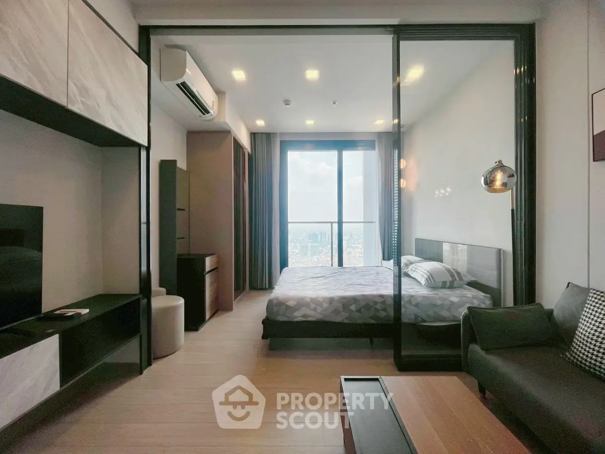 Modern bedroom with floor-to-ceiling windows and city view, featuring sleek furniture and stylish decor.