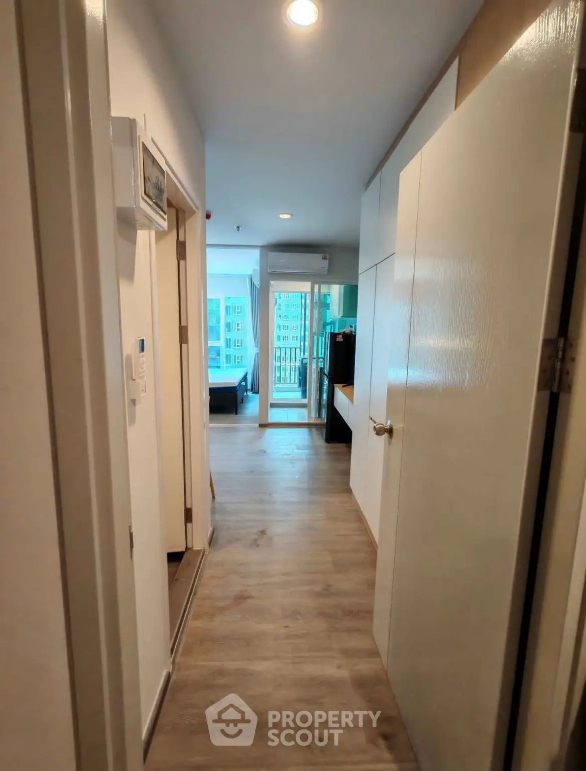 Modern apartment hallway leading to a bright living area with balcony view.