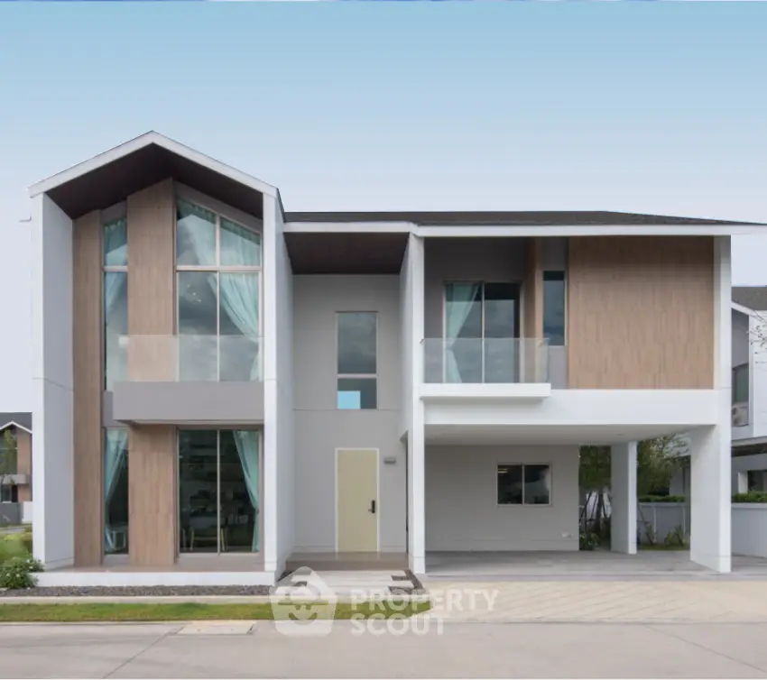 Modern two-story house with large windows and sleek design in suburban neighborhood.