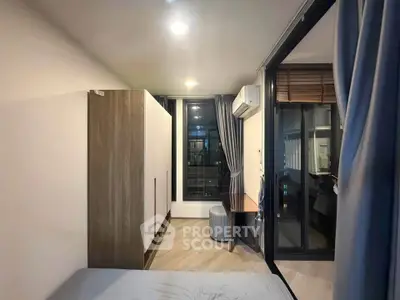 Modern bedroom with large window and stylish decor in a contemporary apartment.