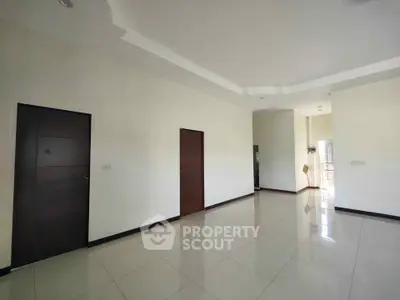 Spacious modern living room with sleek tile flooring and elegant dark wood doors.