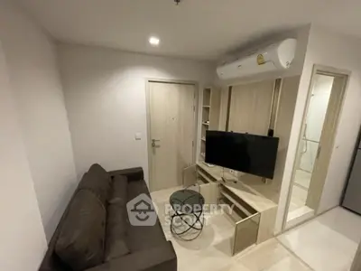 Modern living room with sleek furniture and wall-mounted TV in a cozy apartment.