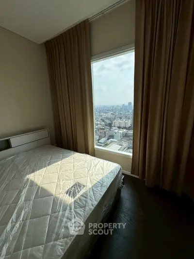 Spacious bedroom with stunning city view from large window, featuring elegant curtains and modern decor.