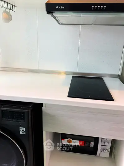 Modern kitchen with sleek induction cooktop and built-in microwave, featuring efficient use of space.