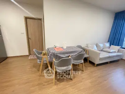 Modern living room with dining area and stylish furniture, featuring wooden flooring and cozy ambiance.