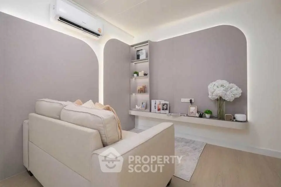Modern living room with elegant decor and built-in shelving, featuring a cozy sofa and air conditioning.