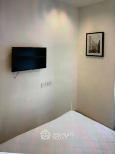 Cozy bedroom with wall-mounted TV and framed artwork, perfect for modern living.