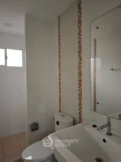 Modern bathroom with sleek white fixtures and colorful tile accents