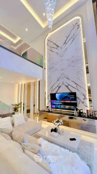 Luxurious modern living room with high ceilings and elegant marble wall design.