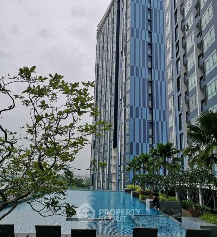 Luxurious high-rise building with stunning poolside view and lush greenery.