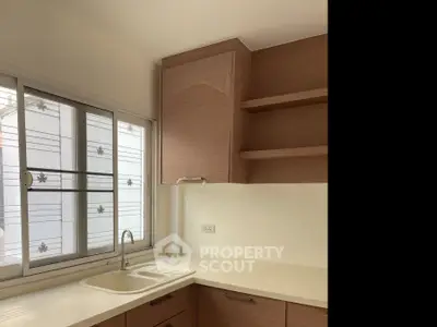 Modern kitchen with sleek cabinetry and large window for natural light.