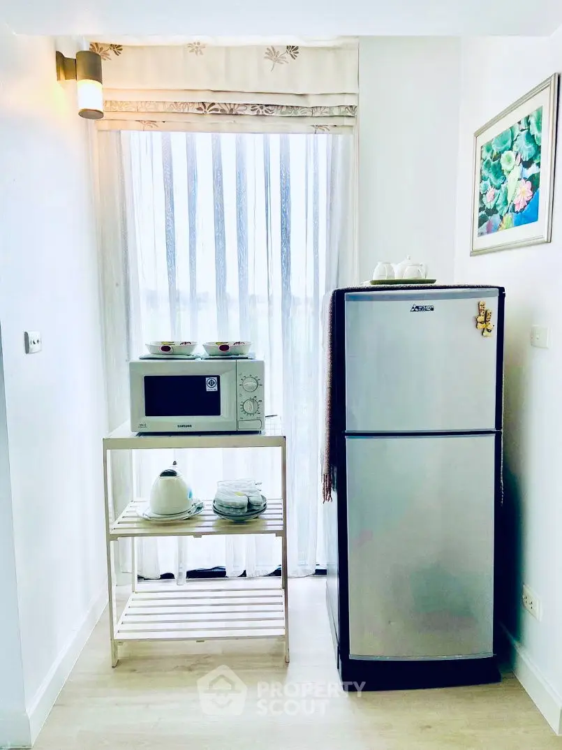 Cozy kitchen corner with fridge and microwave, perfect for compact living spaces.