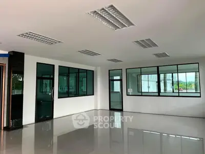 Spacious and well-lit commercial space with reflective flooring, large windows, and modern lighting fixtures, ideal for businesses seeking a professional environment.