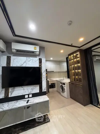 Modern living room with marble TV wall and sleek kitchen featuring washing machine
