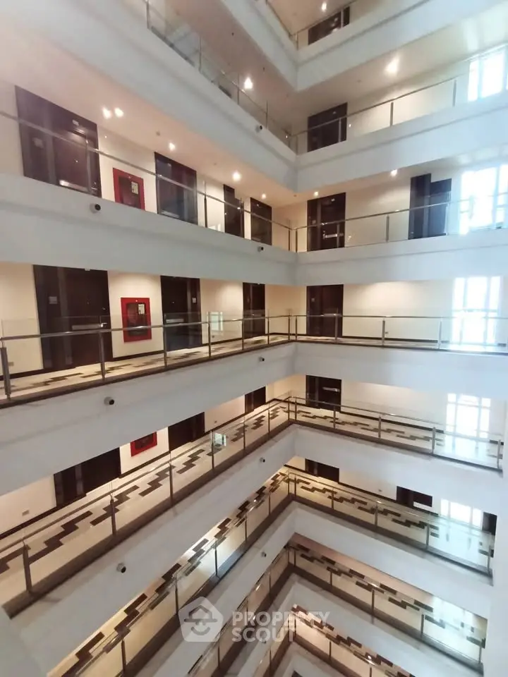 Modern multi-story building interior with open corridors and glass railings.